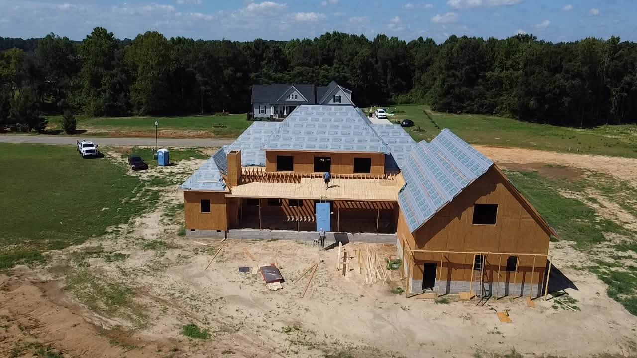 A custom home under construction in Johnston County with crews working on the framing