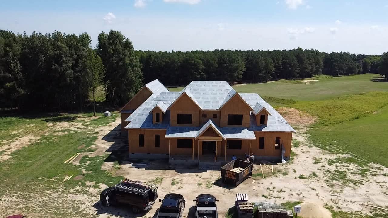 A custom home under construction in Johnston County with the roof framed and dried in