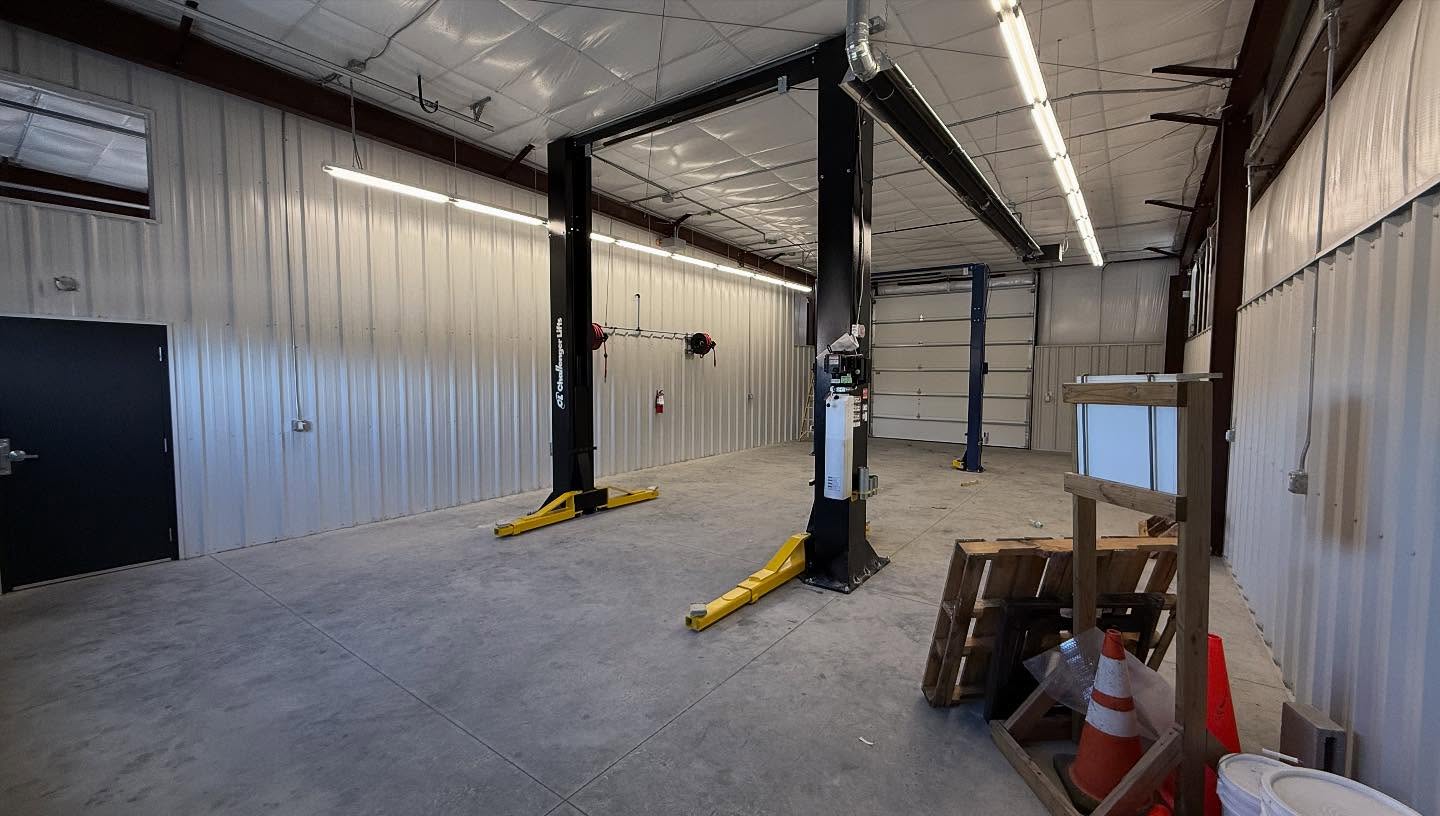 Interior of a finished metal building service bay with insulated steel wall panels, two-post vehicle lifts and a roll-up door