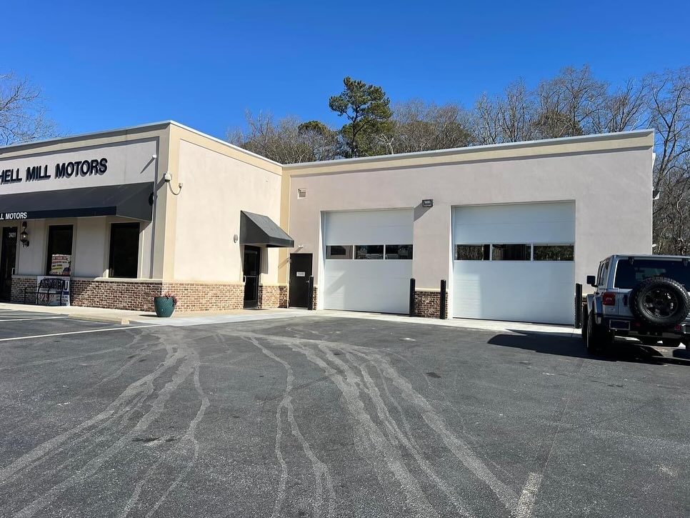 Completed commercial service building for Mitchell Mill Motors, with stucco and brick elevation, two roll-up service bay doors and a paved lot