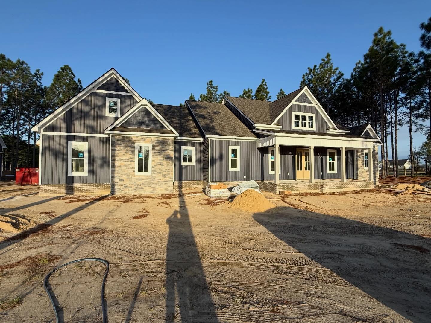Finished custom home exterior in dark board and batten siding with stone and brick accents and a covered front porch