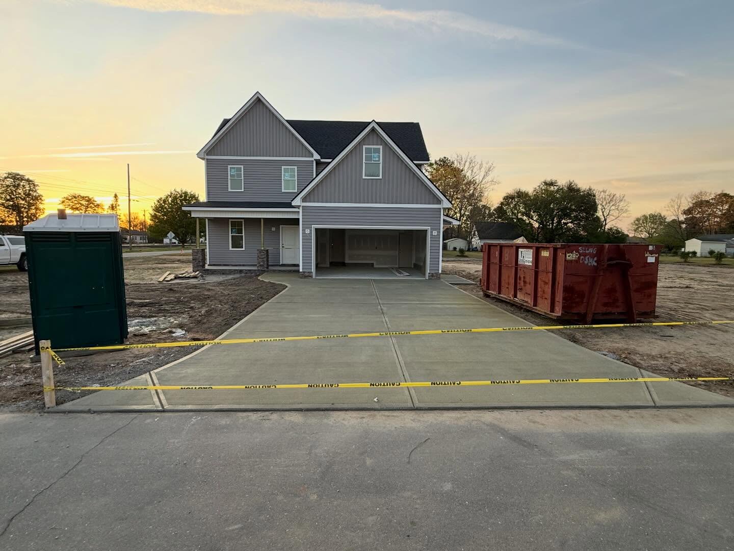 Custom home at dusk with exterior stone on the porch columns and a freshly poured concrete driveway