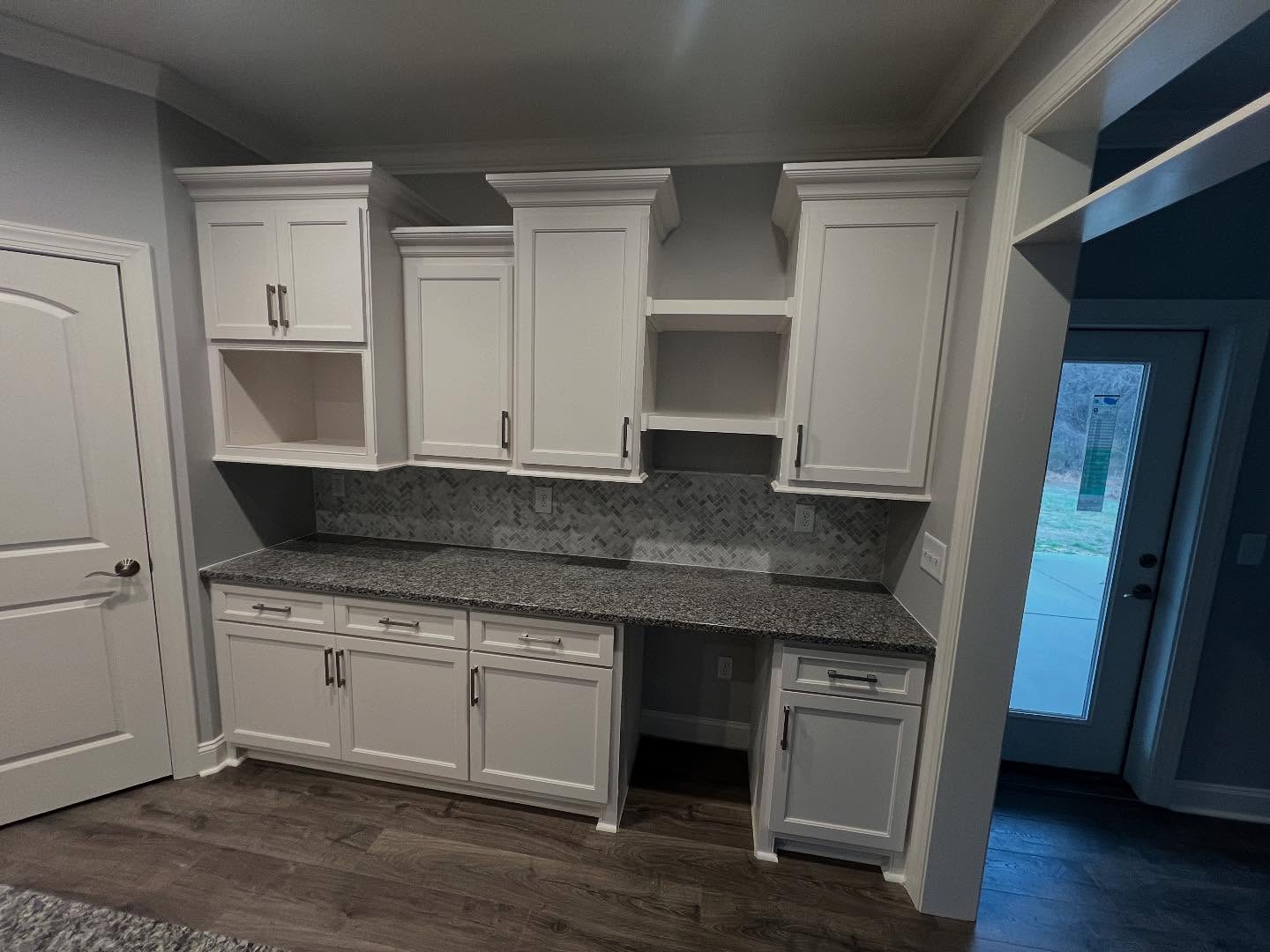 Butler's pantry and coffee bar with white cabinetry, granite countertop, herringbone tile backsplash and open display shelving