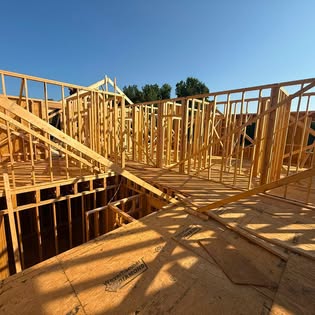 Interior framing of a custom home showing stud walls, floor decking and a framed stair opening
