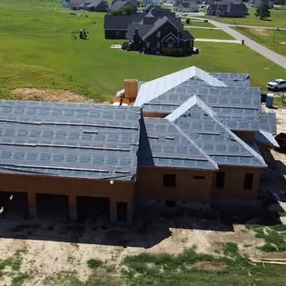 Aerial view of a custom home under construction in an established neighbourhood