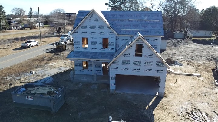 Two story home with framing complete and housewrap installed, seen from above on a winter day