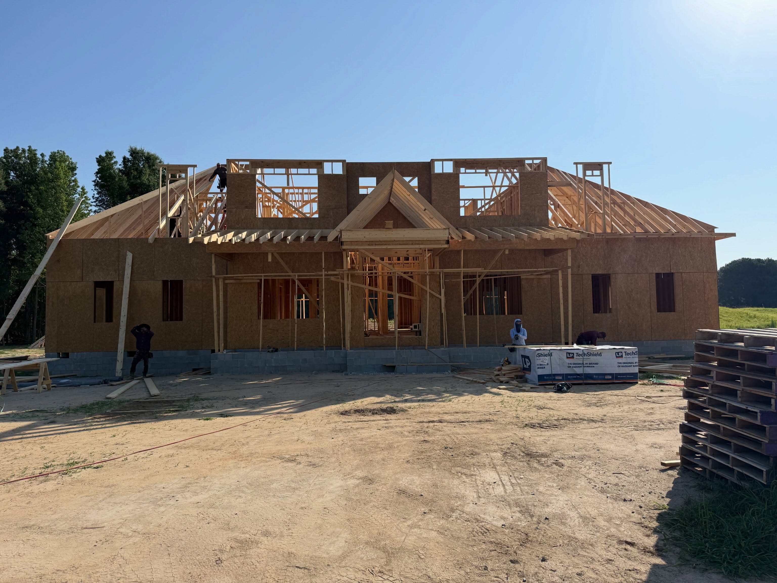 Custom home during framing with the roof structure being set and sheathing partly installed